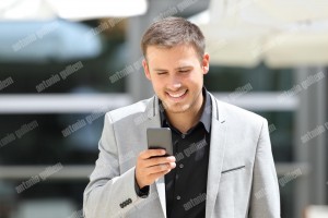 Businessman walking and texting on phone (1)
