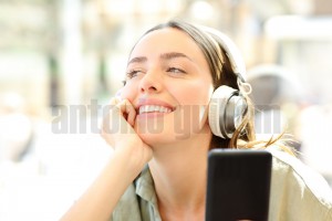 Happy woman is listening to music in a coffee shop