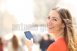 Happy woman walking in the street using a smartphone