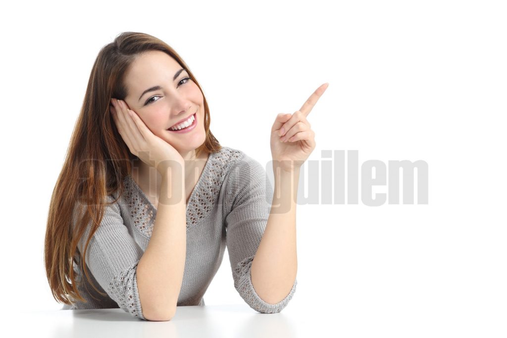 Happy woman pointing and presenting at side looking at camera isolated on a white background