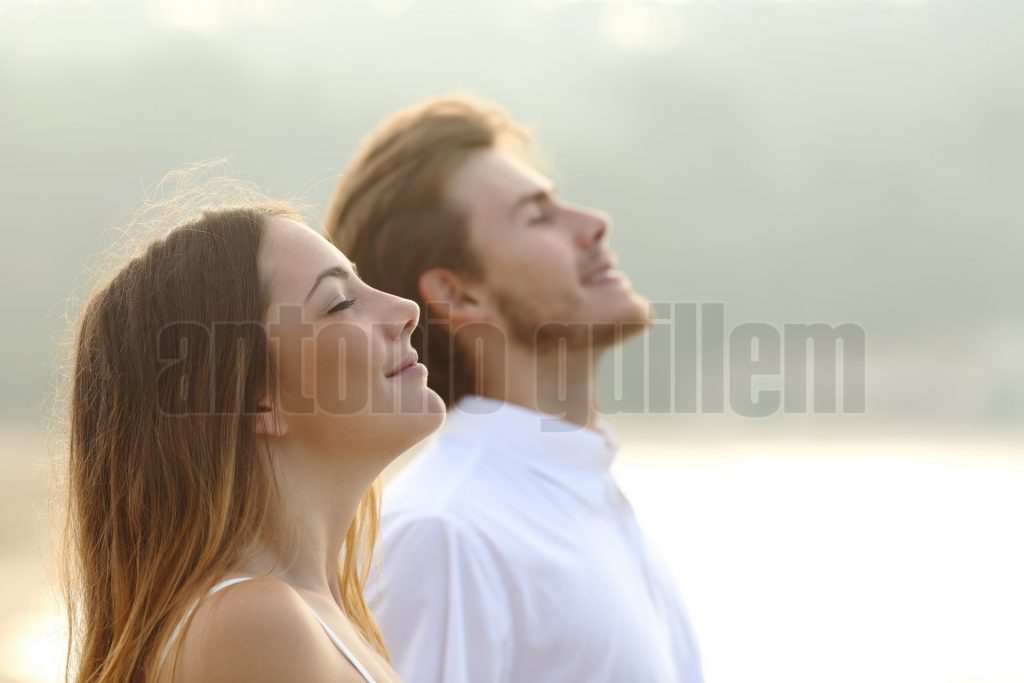 Profile of a couple of man and woman breathing deep fresh air together at sunset