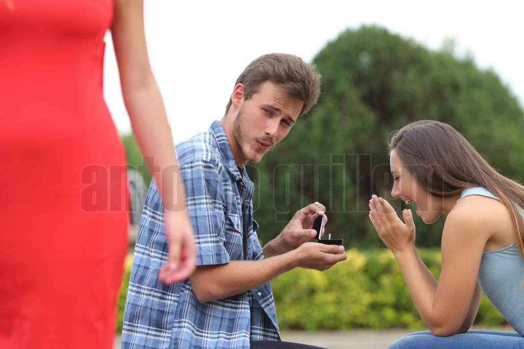 Cheater man cheating during a marriage proposal with his innocent girlfriend