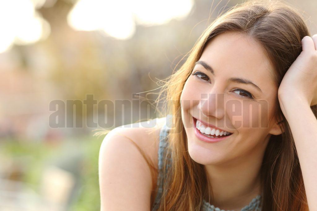 Woman smiling with perfect smile and white teeth in a park and looking at camera