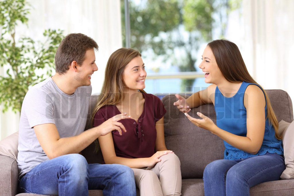 Three joyful friends talking on a couch at home