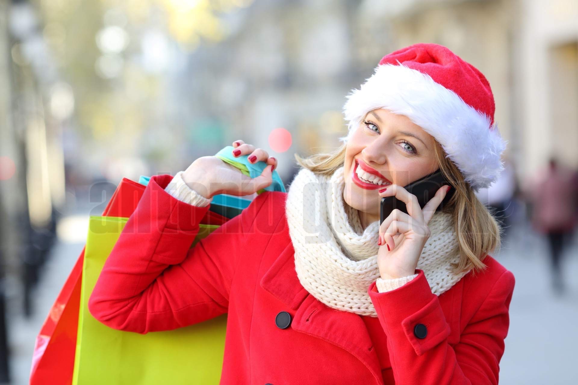 Happy shopper with shopping bags calling on phone in christmas