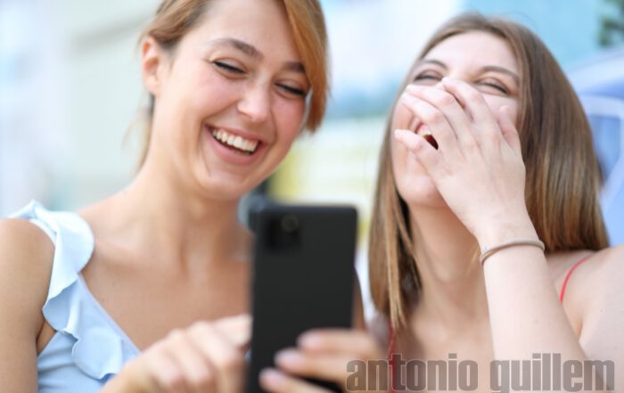 Two girls laughing with a mobile phone