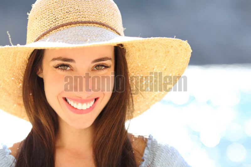 Modelo de stock sonriendo a camara en una playa durante una sesion de fotografia