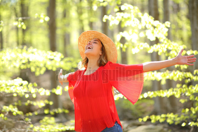 Excited woman spreading in a green forest a sunny day