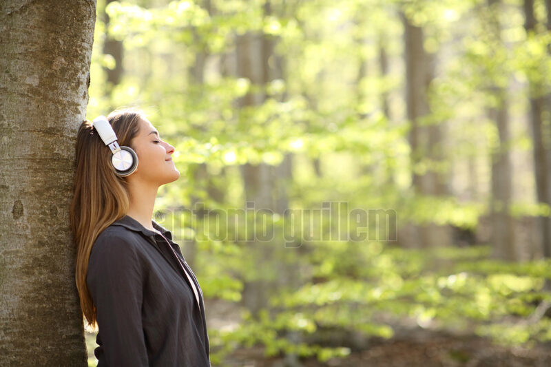 Woman resting listening to music in a forest