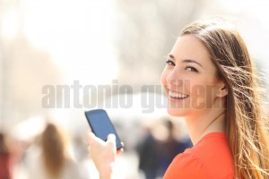 Happy woman walking in the street using a smartphone (1)